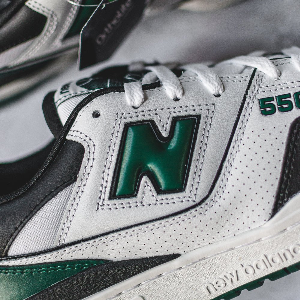 New Balance 550 sneakers in white, green, and black.