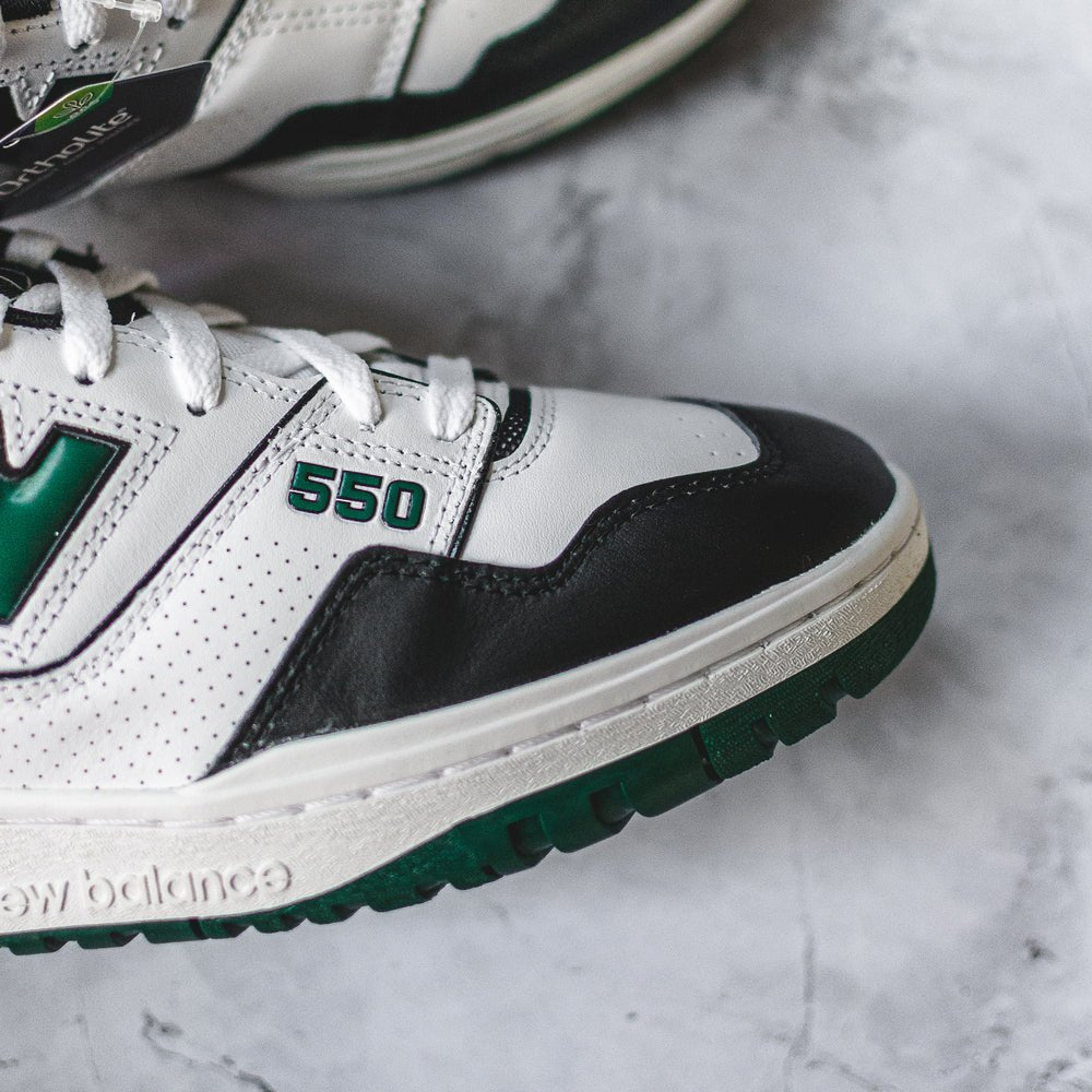 New Balance 550 sneakers in white, green, and black.