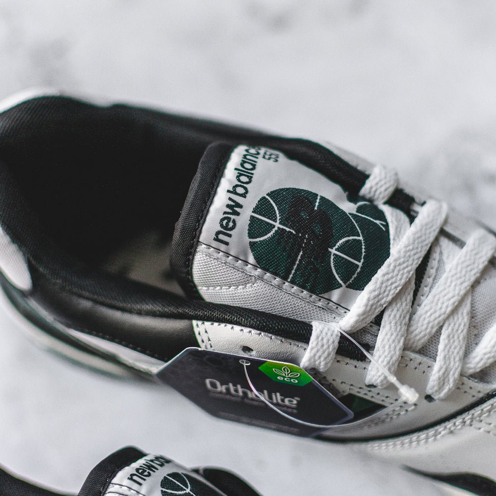 New Balance 550 sneakers in white, green, and black.