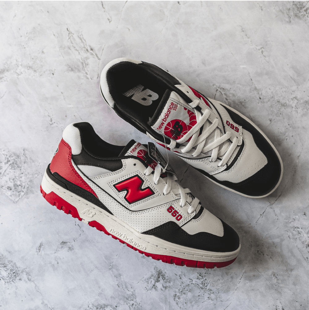 New Balance 550 sneakers in white, red, and black color.