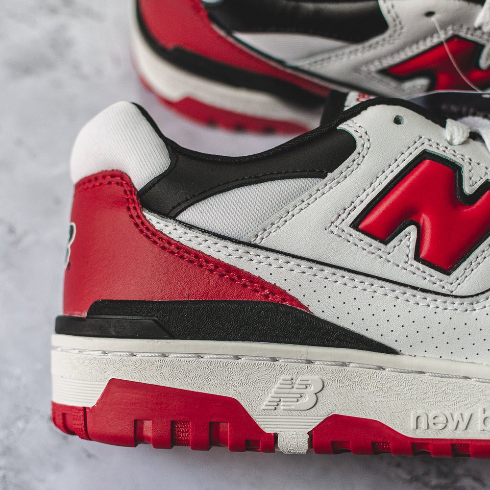 New Balance 550 sneakers in white, red, and black color.